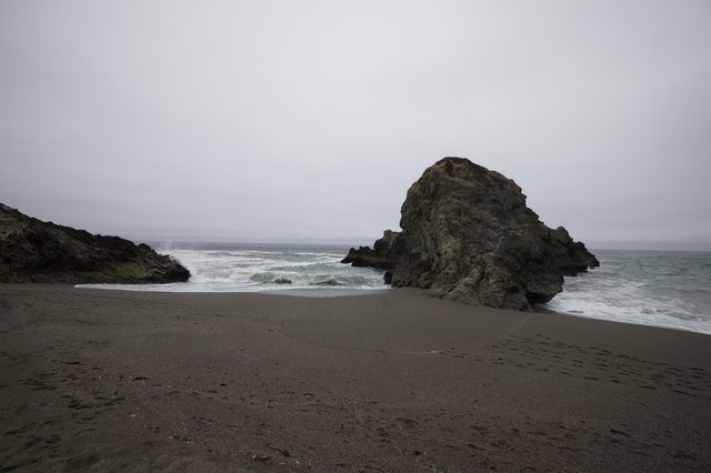 Moody Sea Stack on a Desolate Fog-Shrouded Beach
