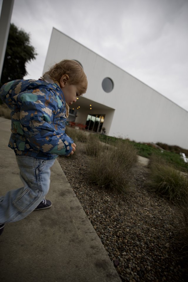 Child Exploring Modern Architecture in Overcast Weather