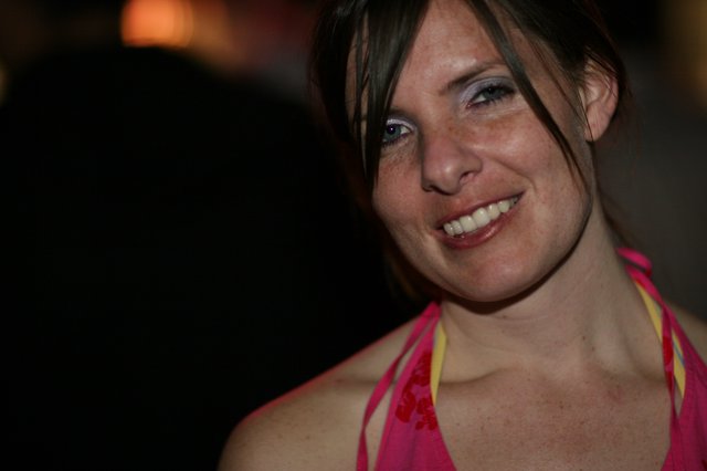 Smiling Woman in Pink at a Nighttime Event