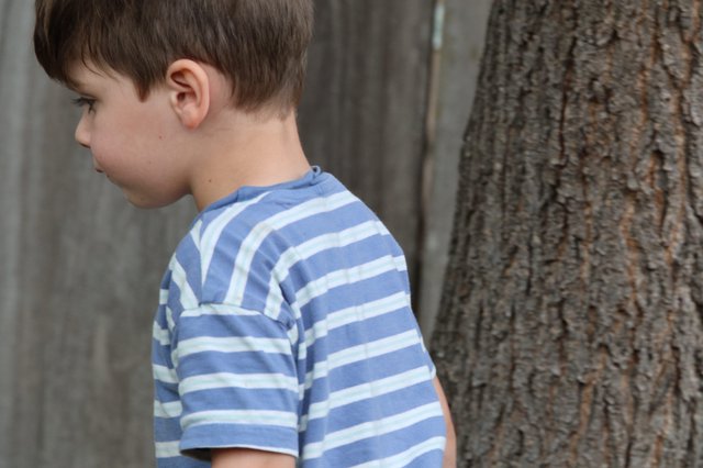 Young Boy in Striped Shirt Near Tree