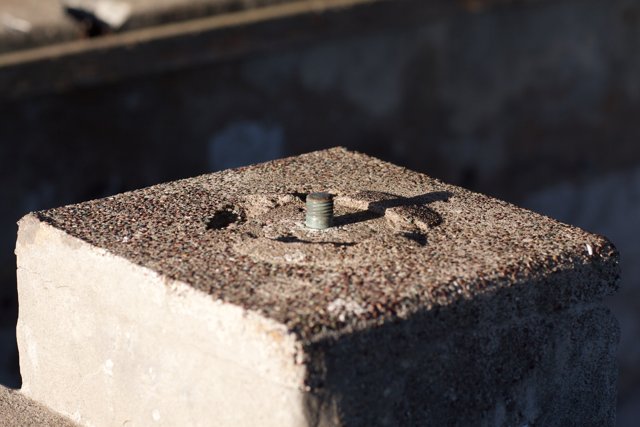 Industrial Heritage: A Rusty Screw on Cement Block