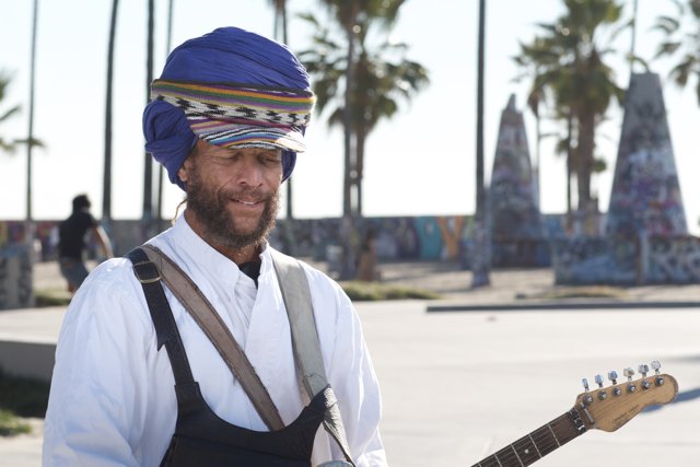 Guitar-strumming Man in Turban Amidst Palm Trees