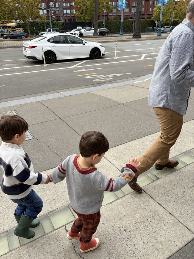 Father and Two Sons Walking on Urban Sidewalk
