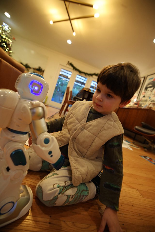 Child Interacting with White Humanoid Robot at Home