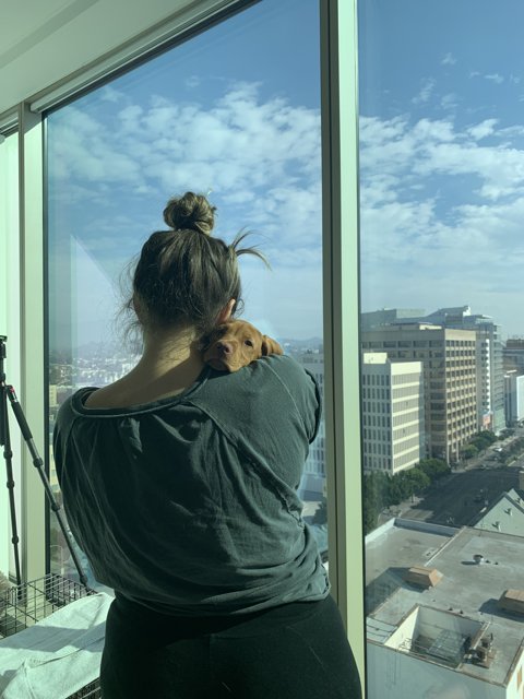 Woman and Her Canine Companion Enjoy the View from a High-Rise Balcony in Downtown LA