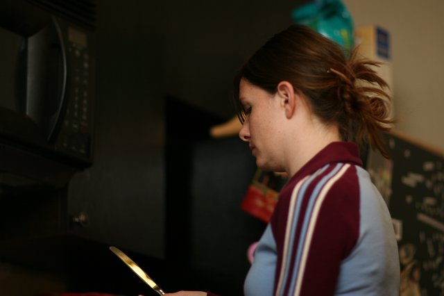 Young Woman Focused in Dimly Lit Kitchen