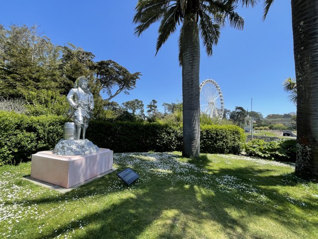 Statue in a Park with Palm Trees and Ferris Wheel