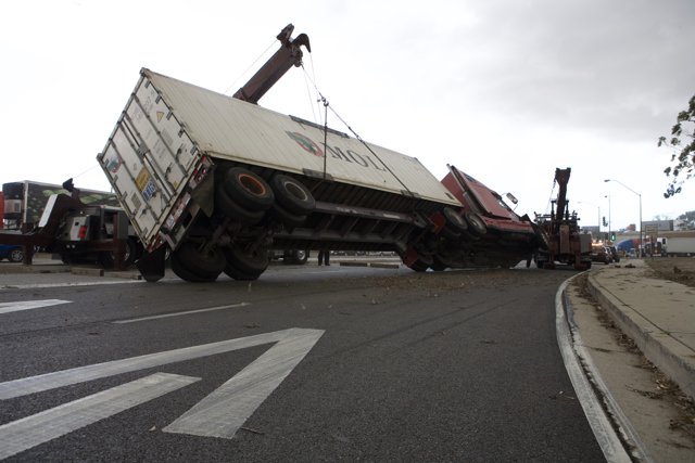 A Crane Lifts an Overturned Truck on Tarmac