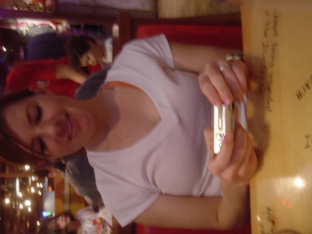 Woman Smiling with Compact Camera at Restaurant