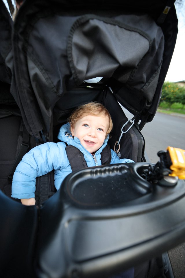 Happy Toddler in Blue Jacket on Stroller Walk