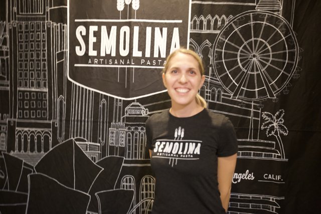 Smiling Woman Poses in Front of Semolina Sign