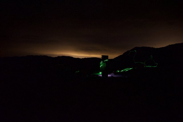 A Green Laser Illuminating a Mountain at Night