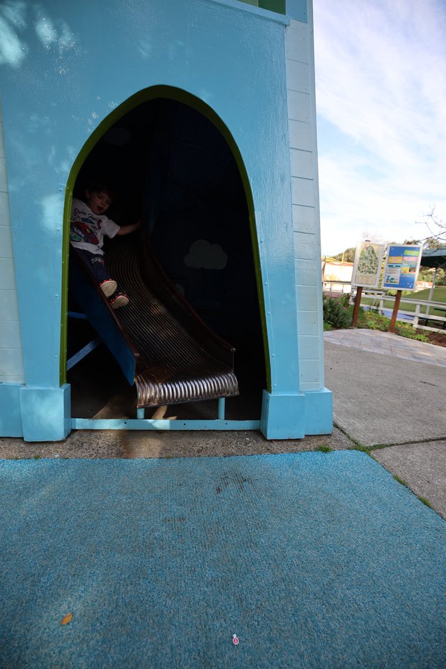 Child Playing in Blue Tunnel Slide at Playground