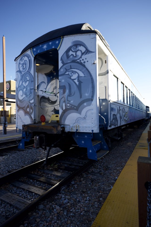 Artistic Train Car with Blue Swirl Murals at Station