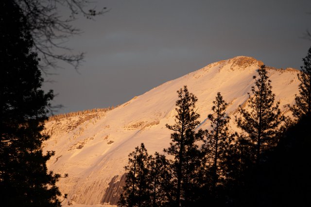 Golden Alpenglow on Snow-Covered Mountain Peak at Dusk