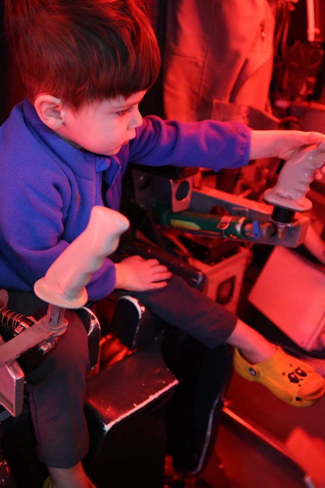 Young Boy Exploring Interactive Science Exhibit Under Red Light
