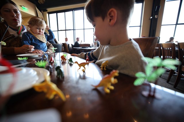 Children Playing with Dinosaur Toys at Restaurant Table