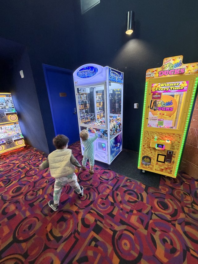 Children Playing Arcade Claw Machines in Game Room