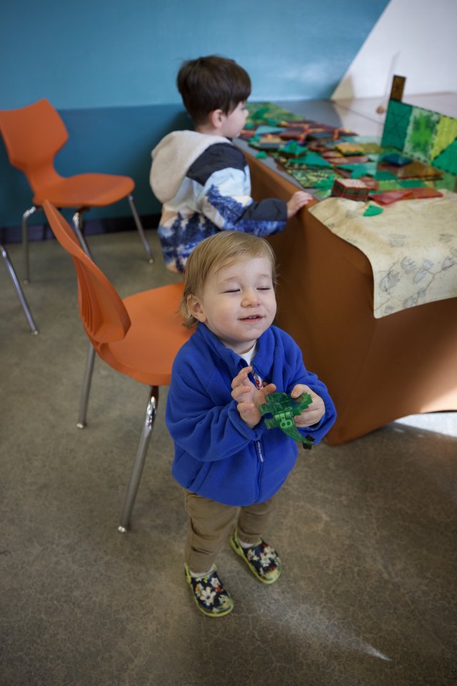 Young Child Playing with Green Toy in Classroom Setting