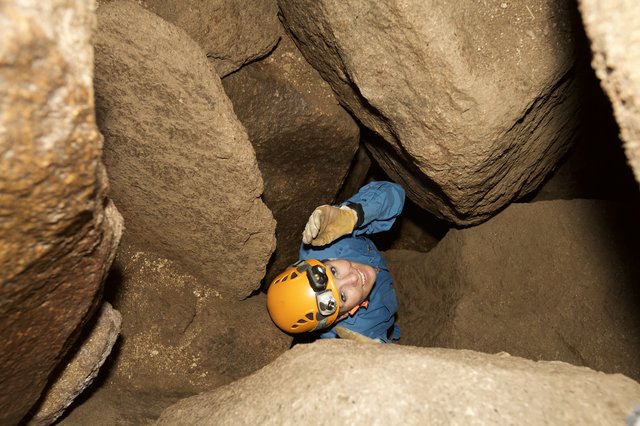Caver Squeezes Through Tight Rocky Passage Underground