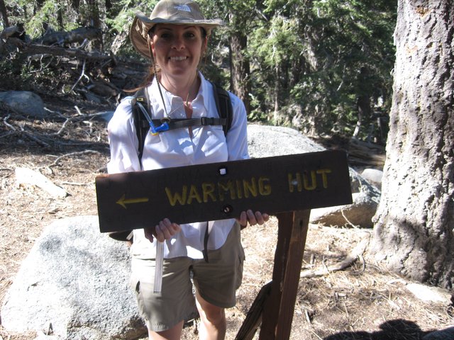 Hiker Poses at Warming Hut Trail Sign