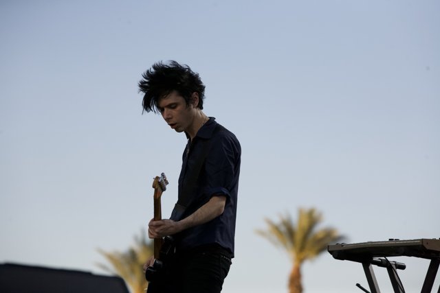 Nick Zinner performs on stage under the blue sky