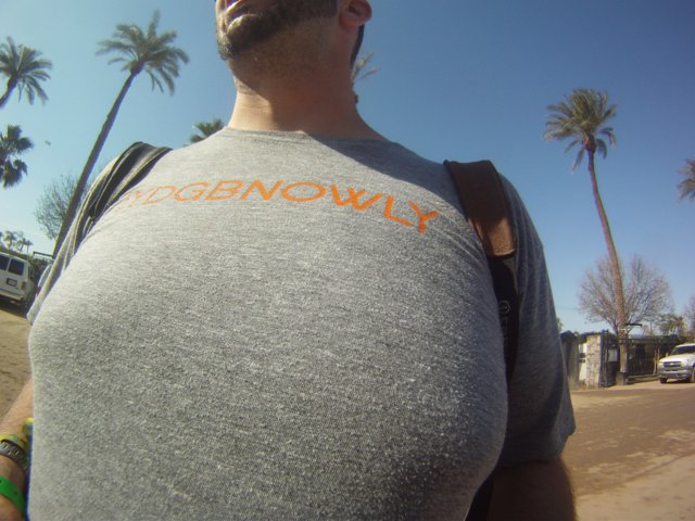 Man in Grey T-Shirt with Orange Logo Standing Outdoors