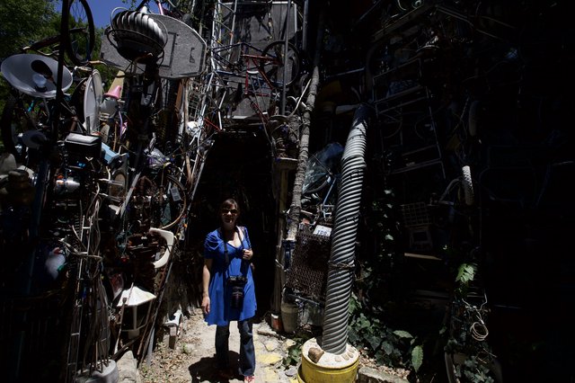 Woman Surrounded by Towering Walls of Salvaged Junk Art