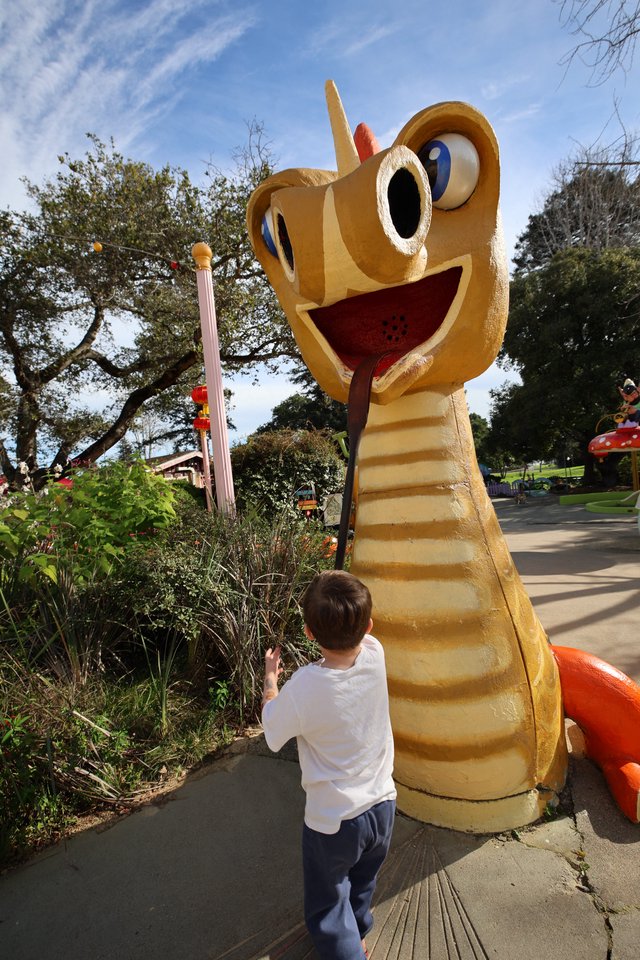 Child Encounters Whimsical Giant Snake Sculpture in Park