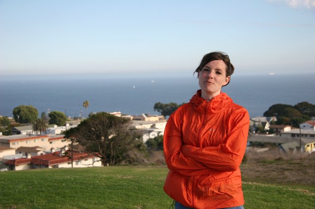 Woman in Orange Jacket Overlooking Coastal Town