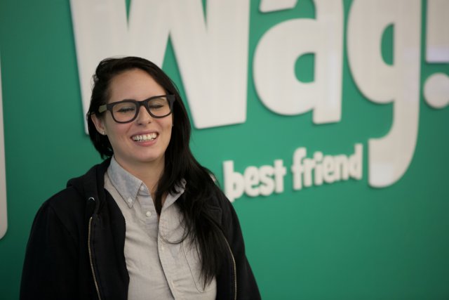 Happy Woman in Glasses Poses in Front of Wag Sign