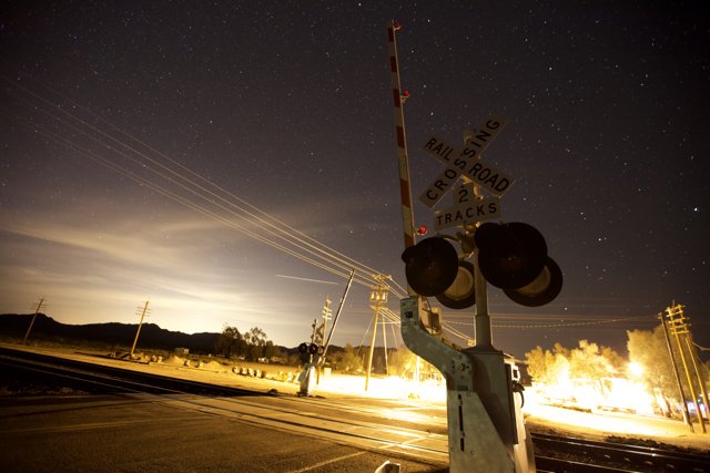 Nighttime Railroad Crossing under a Starry Sky
