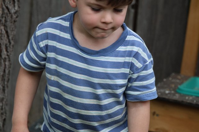 Young Child in Striped Shirt Looking Down Outdoors
