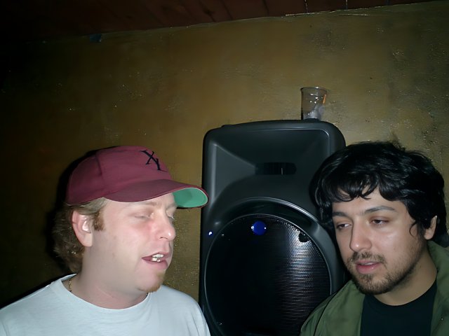 Two Men Stand Proud in Front of a Speaker