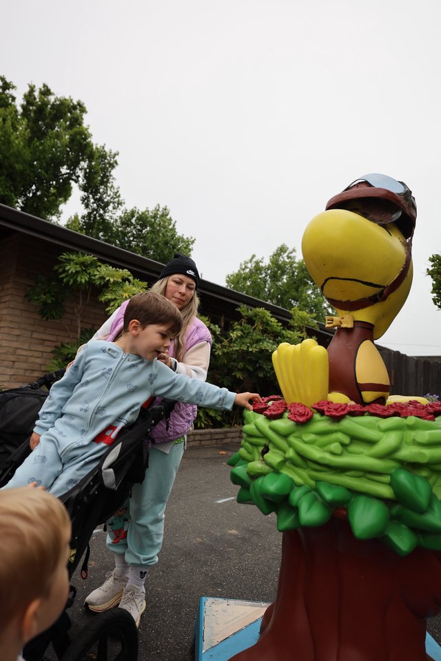 Child Touches Woodstock Statue at Theme Park