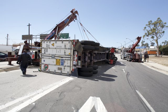 Crane lifting overturned truck on street