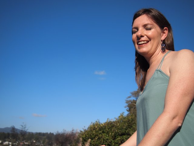 Joyful Woman Laughing Under Clear Blue Sky