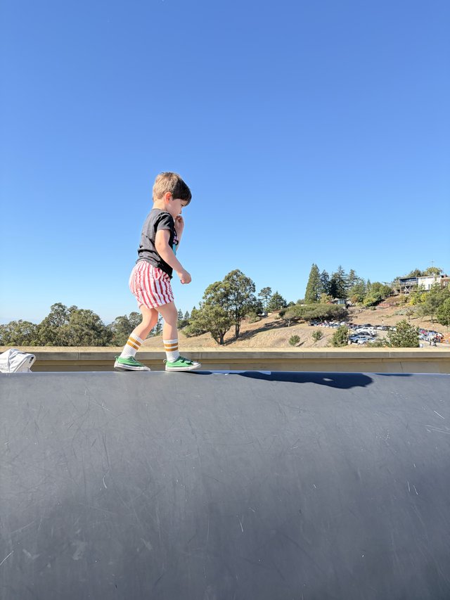 Young Boy Walking on Rooftop Against Clear Blue Sky