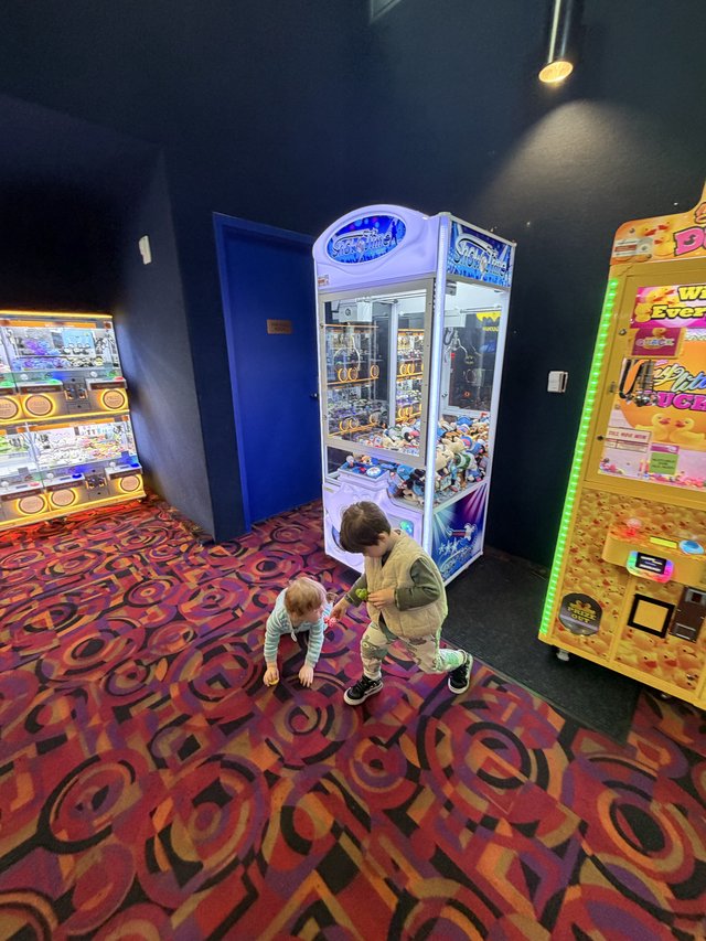 Two Children Playing at Arcade Claw Machine