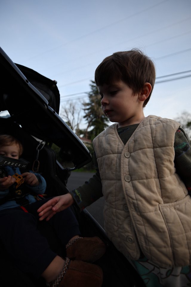 Young Boy Exploring Car Trunk on Suburban Street