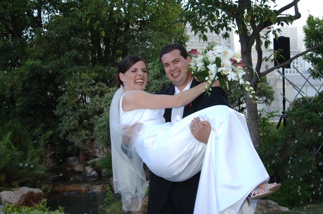 Joyful Groom Carries Laughing Bride in Garden