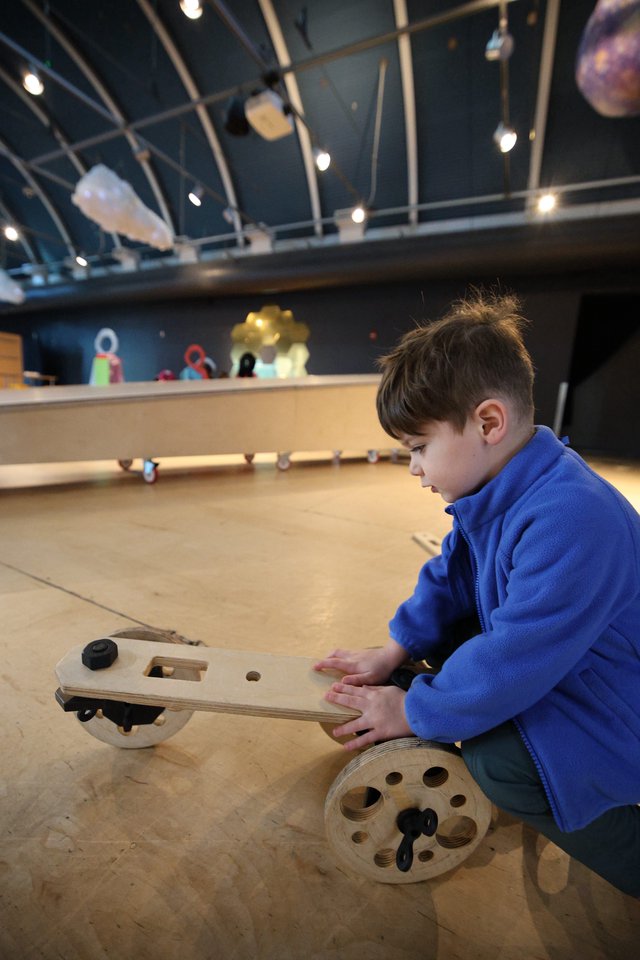 Young Inventor Building Wooden Vehicle at Science Center