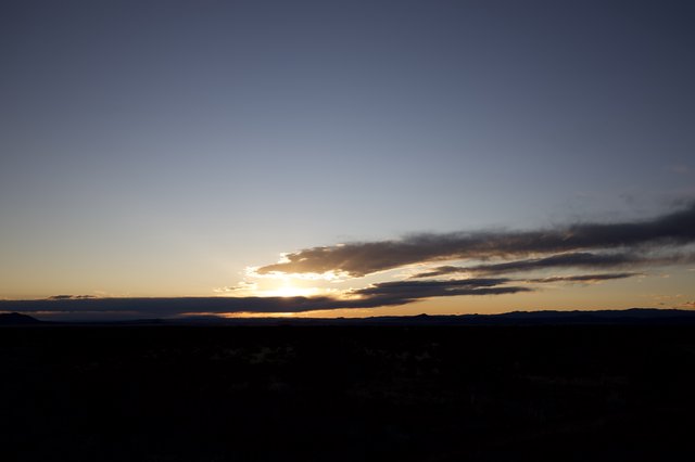 Dramatic Desert Sunset Over Distant Mountain Range