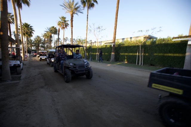 Coachella Cruise Caption: Nine festival goers take a joy ride on a golf cart down a rustic road, taking in the sights of palm trees and shrubs amidst a blue sky.