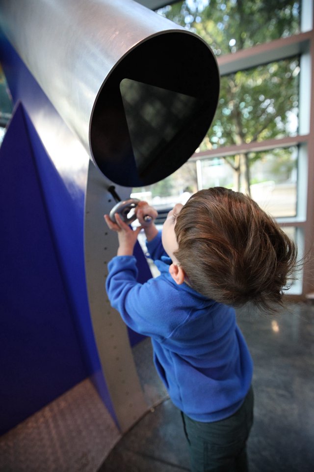 Young Child Exploring Interactive Telescope Exhibit at Science Center