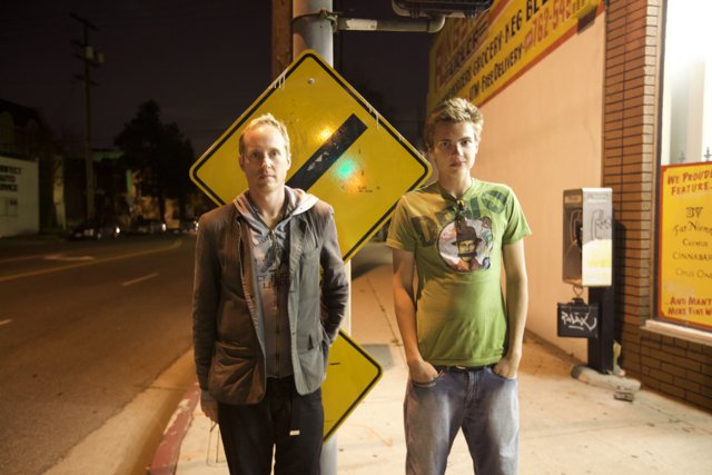Two Men Standing by the Street Sign at Night
