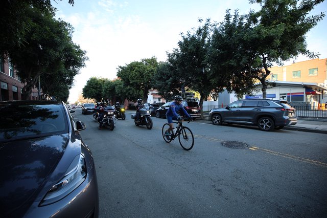 Urban Cyclist Shares Street with Motorcycles at Dusk