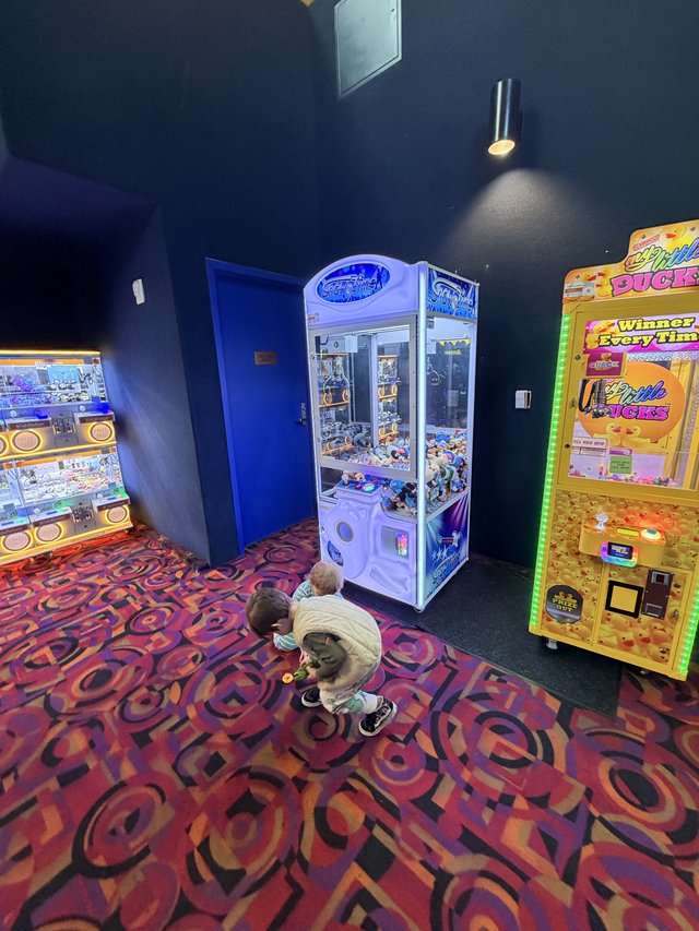 Children Playing Arcade Claw Machines at Entertainment Venue