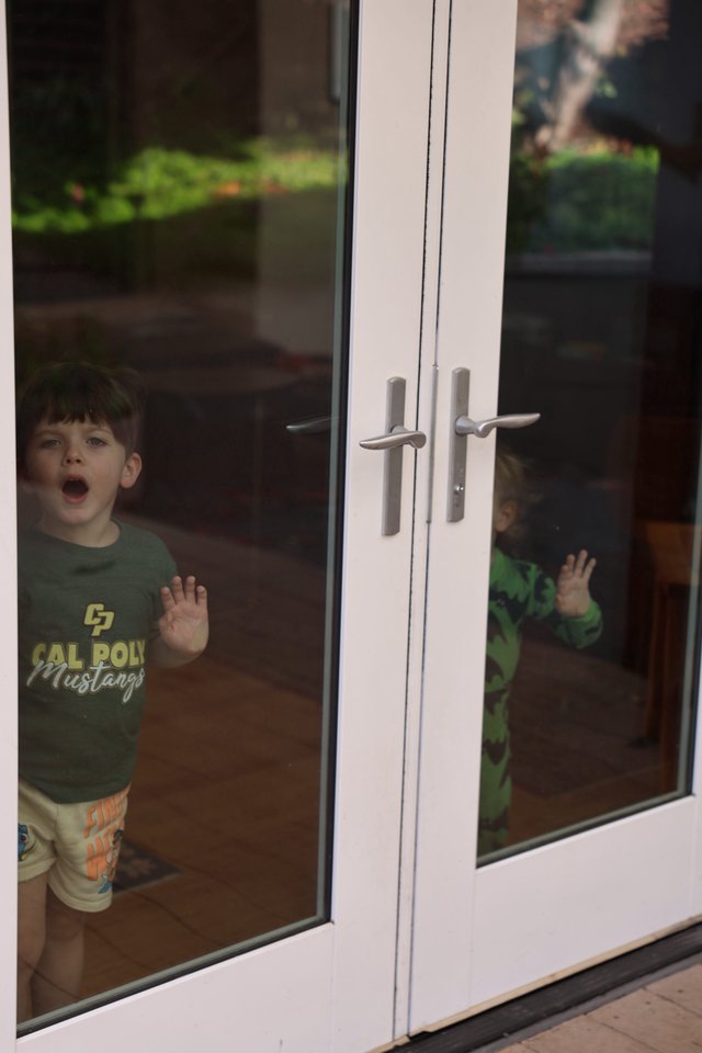 Young Boy Locked Outside Behind Glass Door