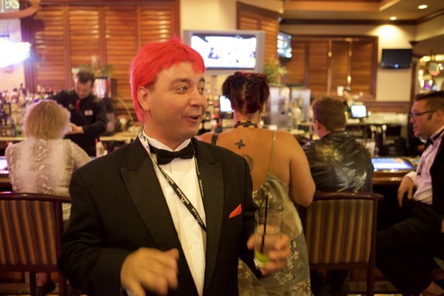Red-Wigged Man in Tuxedo Enjoys a Drink at the Bar